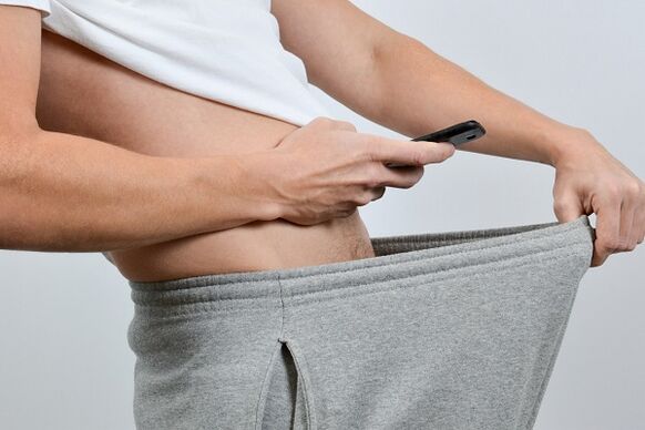 mees vaatab pükstest alla laienenud peenise poole